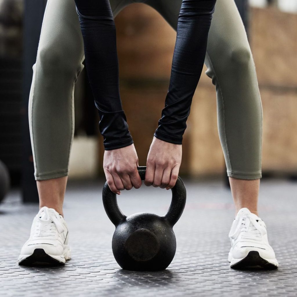 Mujer entrenando potencia con pesa rusa en postura correcta durante la perimenopausia